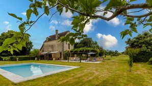 A house with a swimming pool, a garden, and a patio area.