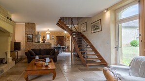 A spacious living room with a fireplace, a staircase, and a view of the outside.
