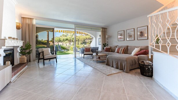 A spacious living room with a fireplace, a sofa set, a dining area, and a view of the outdoors.