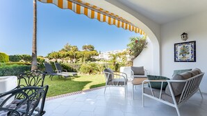 A patio with outdoor furniture, a view of a garden, and a tiled floor.