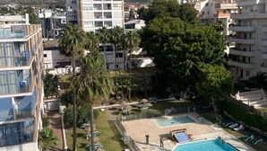 Un quartier résidentiel doté d’une piscine, de palmiers et offrant une vue sur les montagnes lointaines.
