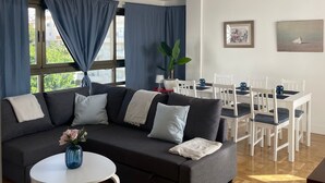 Un salon moderne comprenant un canapé, une table à manger, des chaises et une petite table blanche sur laquelle est posé un vase.