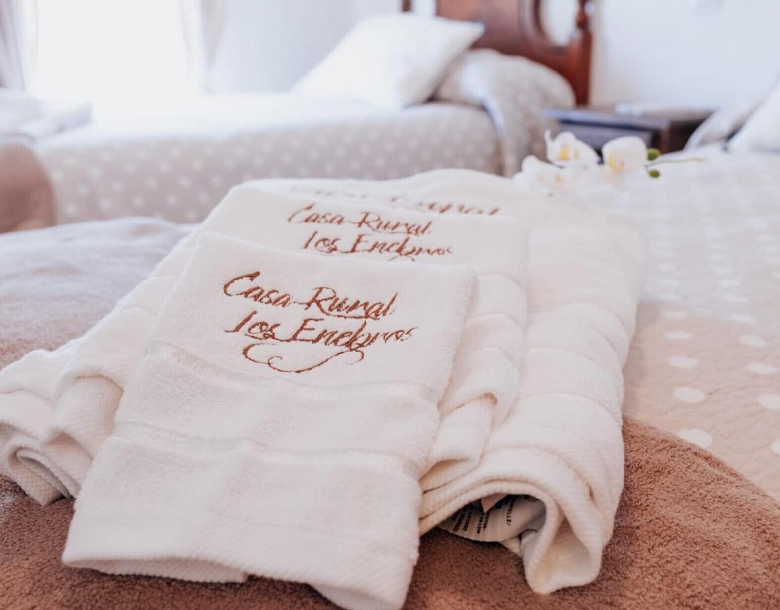Een keurig opgevouwen witte handdoek met tekst op een bed in een hotelkamer.