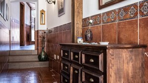 A hallway with a wooden bench, a tiled wall, a mirror, and a decorative vase. - Holiday Home 'Casa Rural Los Enebros' with Private Pool, Wi-Fi and Air Conditioning (Los Navalucillos)