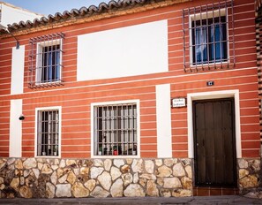 Un edificio de ladrillo rojo con marcos de ventana blancos, zócalo de piedra y puerta negra.