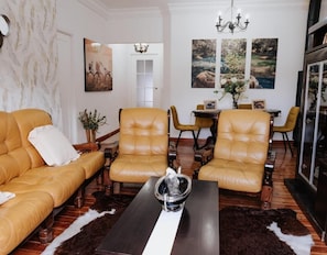 Un salon comprenant un canapé, deux fauteuils, une table basse et un coin repas avec des chaises et une table.