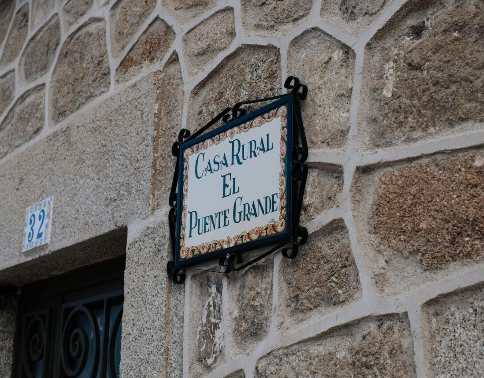 Eine Steinsäule mit dem Schriftzug 'CASA RURAL EL PUENTE GRANDE'.