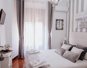 Une chambre à coucher bien rangée, avec un lit, des rideaux, une table de chevet avec une lampe et un miroir au mur.