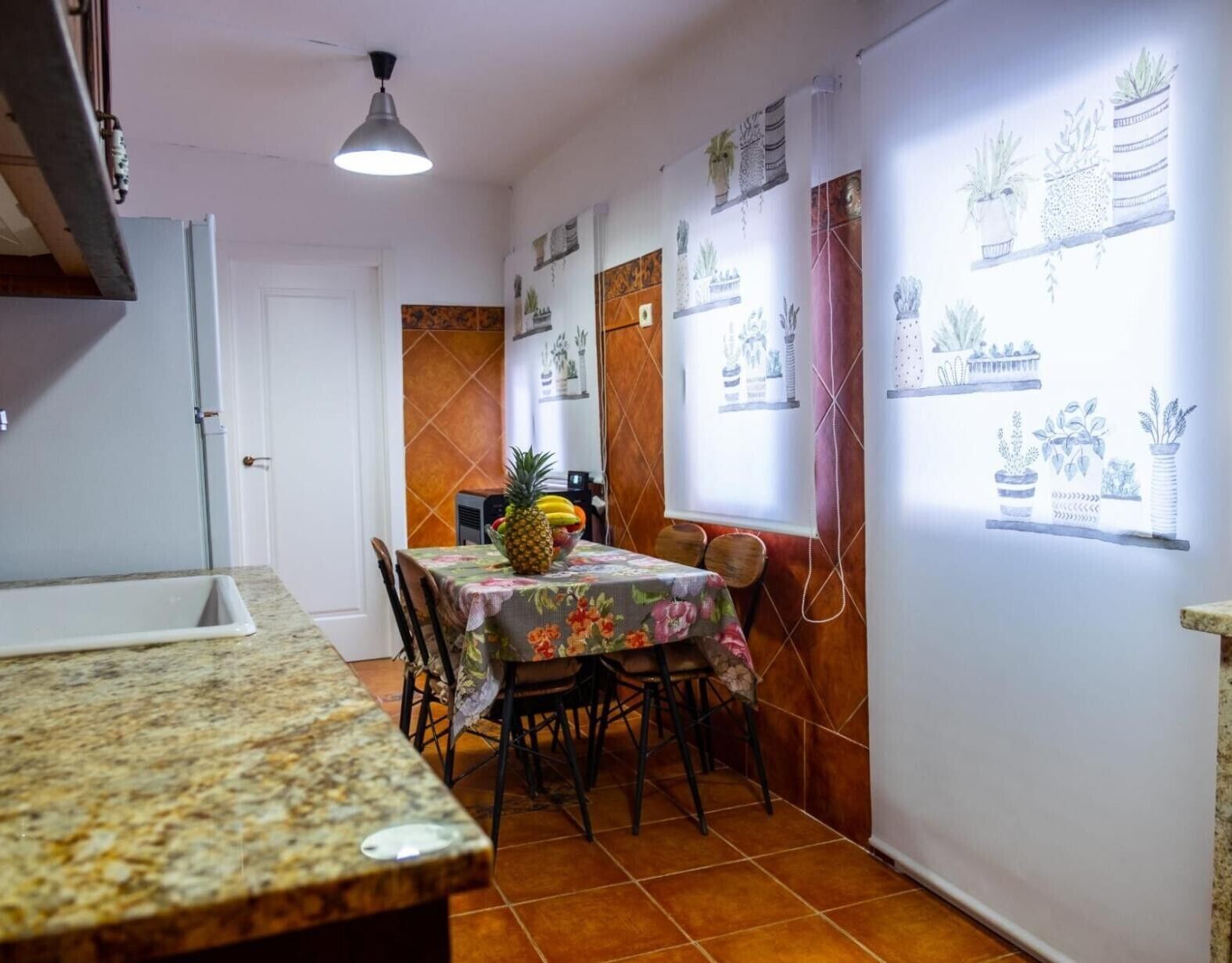 Un comedor con una mesa dispuesta para dos personas, un frutero y una encimera de cocina.