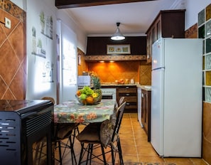 Une cuisine équipée d’une table à manger, de chaises, d’un réfrigérateur et d’un four à micro-ondes.