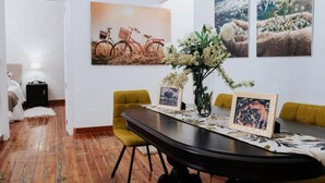 Een eethoek met een houten tafel, gele stoelen en lijstwerken.