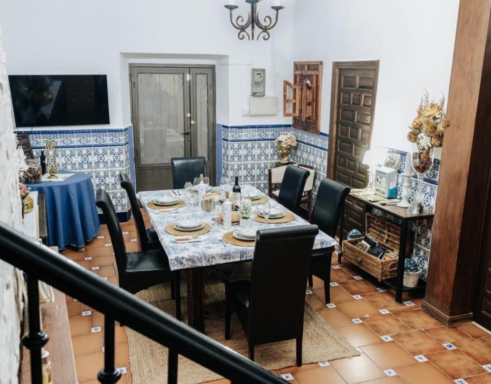 Un comedor con una mesa preparada para cuatro, sillas, un televisor y elementos decorativos.