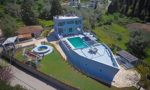 Un edificio moderno con piscina sul tetto, una fontana circolare e un piccolo pontile per barche.