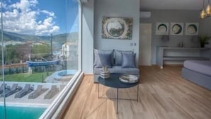 A modern living room with a large window, a sofa, a coffee table, and artwork on the wall. - Villa 'Boat' with Sea View, Wi-Fi and Air Conditioning (Ellomeno)