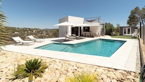 Une maison moderne dotée d’une piscine, de mobilier d’extérieur et offrant une vue sur le paysage.