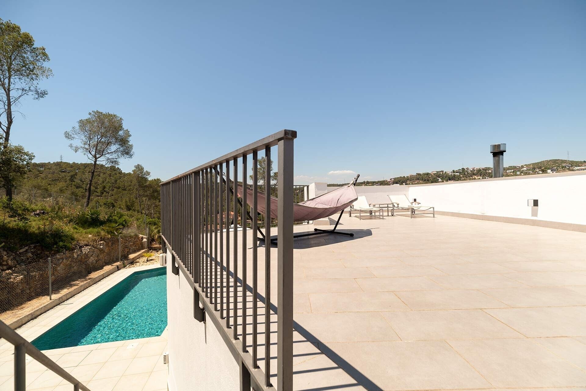 Una terrazza sul tetto con piscina, poltrona relax e vista sul paesaggio circostante.