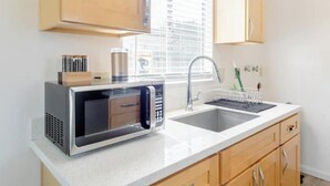 Una cocina con microondas, pileta y armarios de madera.