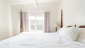 Un dormitorio con una cama grande, un cabecero de madera y una ventana con cortinas estampadas.