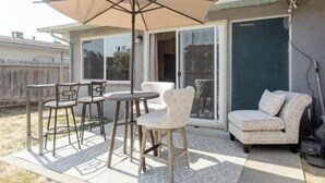 Un patio con una mesa, sillas, un amplio paraguas y un sofá.