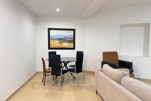 Ein Essbereich mit Tisch, Stühlen, einer Couch und einem Bild an der Wand.
