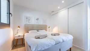 A modern bedroom with a bed, bedside tables, and artwork on the wall. -  Modern Apartment with Sea Views in Higuerón West (Fuengirola)