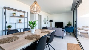 A modern living room with a dining area, a TV, and a large window. -  Modern Apartment with Sea Views in Higuerón West (Fuengirola)