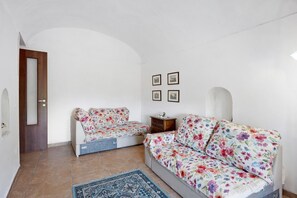 A room with a sofa, a small table, a rug, and a door. - Holiday Home 'Rita Al Vesuvio' with Mountain View, Private Terrace and Private Garden (Terzigno)