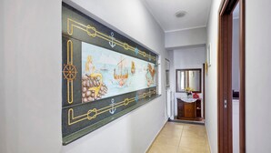 A hallway with a large mural, a wooden door, and a small cabinet with a vase. - Holiday Home 'Rita Al Vesuvio' with Mountain View, Private Terrace and Private Garden (Terzigno)