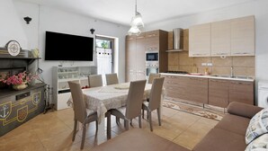 A modern kitchen with a dining area, a flat-screen TV, and a sofa. - Holiday Home 'Rita Al Vesuvio' with Mountain View, Private Terrace and Private Garden (Terzigno)