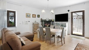 A living room with a sofa, dining table, chairs, a fireplace, and a TV. - Holiday Home 'Rita Al Vesuvio' with Mountain View, Private Terrace and Private Garden (Terzigno)