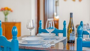 A dining table set with plates, glasses, and cutlery, a bottle of wine, and blue chairs.