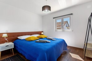 Et soveværelse med seng, natbord, lampe, et vindue og udsigt til en bygning.