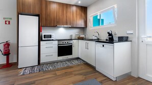 Una cocina moderna con armarios blancos, una campana extractora de acero inoxidable, un microondas, una cafetera y un lavavajillas.