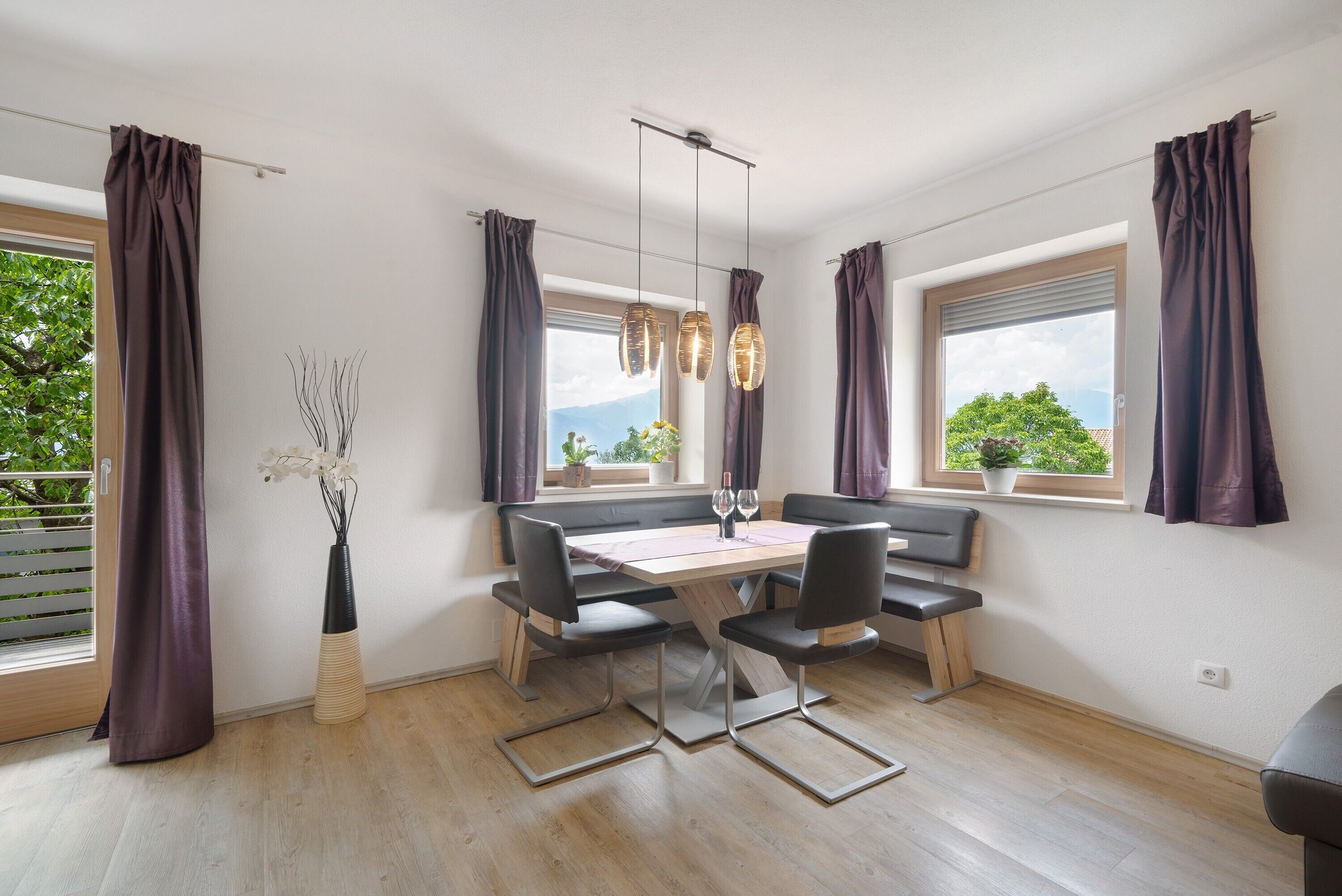 A modern dining area with a wooden table, black chairs, and pendant lights.