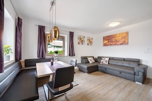 A modern living room with a dining area, a sofa, and a table with chairs.