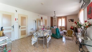 Una habitación con una mesa de comedor, sillas, un sofá, una mesita con un jarrón y un armario.