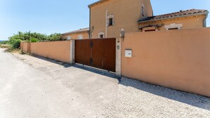 Un edificio con entrada protegida por un portón, techo plano y pared color beige.