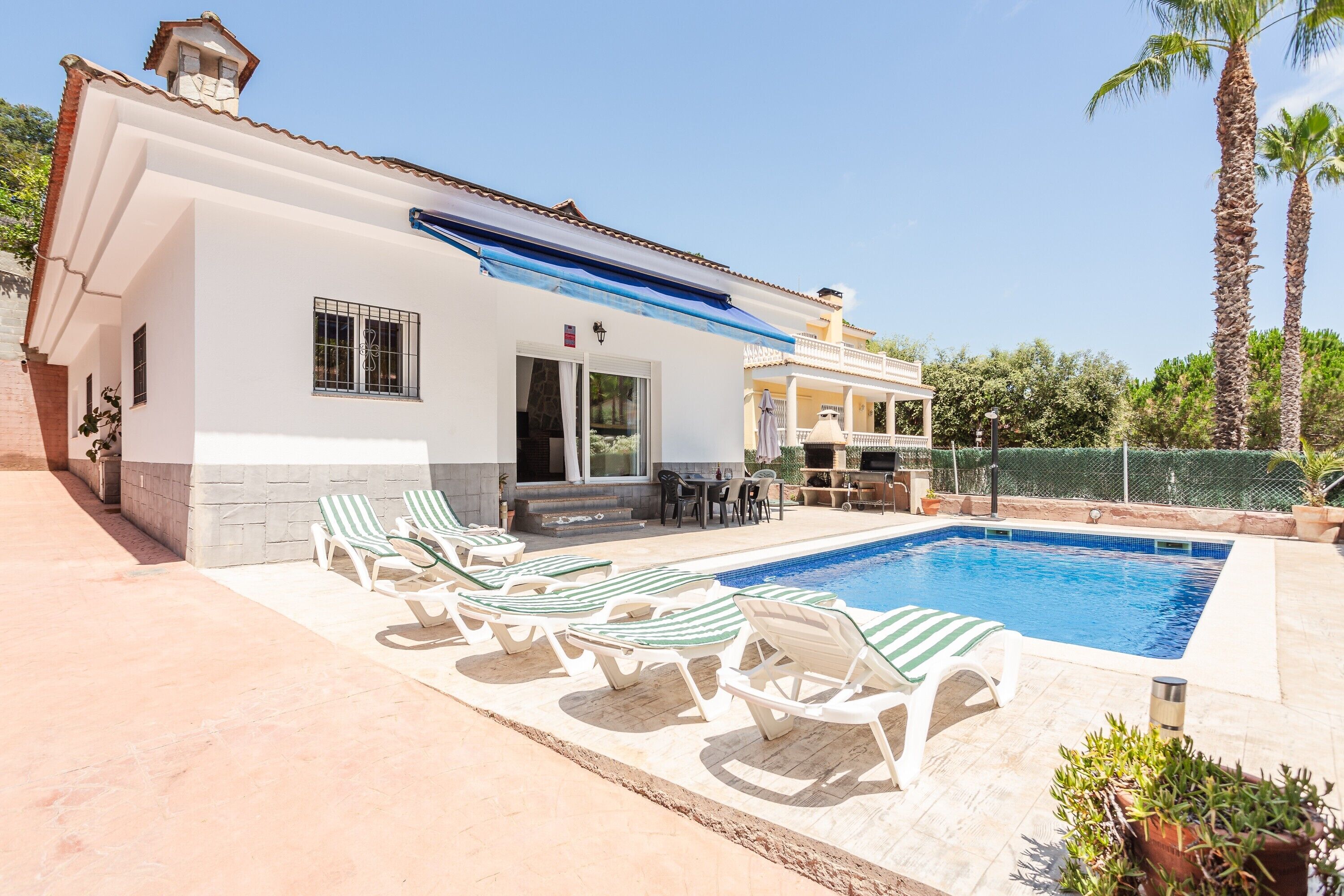Ein Haus mit Swimmingpool, Liegestühlen und einer Terrassenfläche.