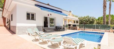 Ein Haus mit Swimmingpool, Liegestühlen und einer Terrassenfläche.