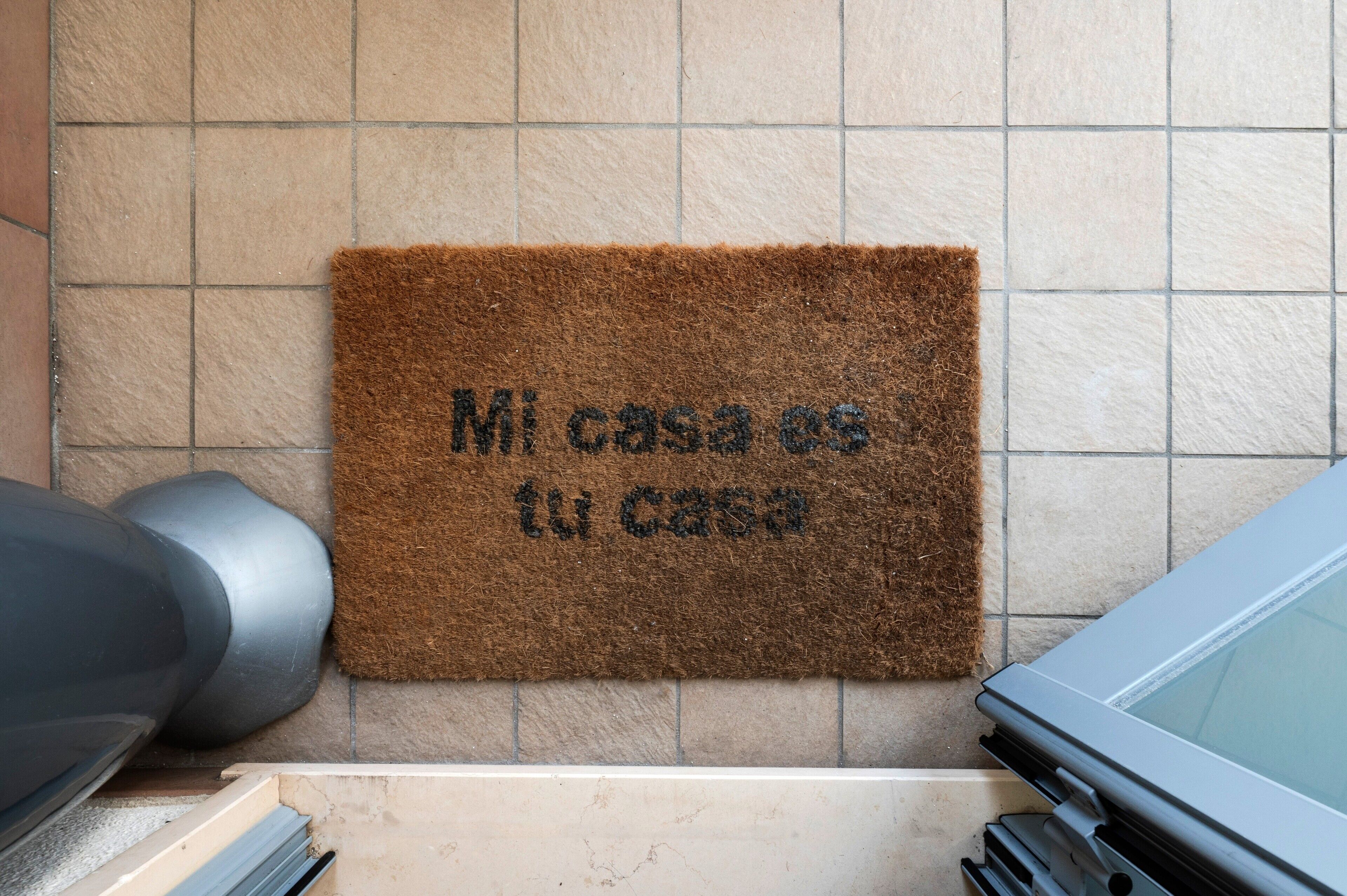 A brown doormat with 'Mi casa es tu casa' text on a tiled wall.