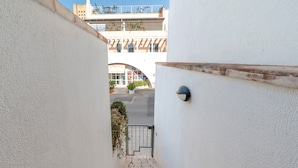 Una escalera estrecha que lleva a una entrada con puerta, con un edificio al fondo.