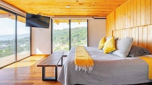 A modern bedroom with a large bed, a bench, and a TV mounted on the wall. - LUXO Casa Valle de Bravo con jacuzzi y espectacular Vista al Lago (Valle de Bravo)