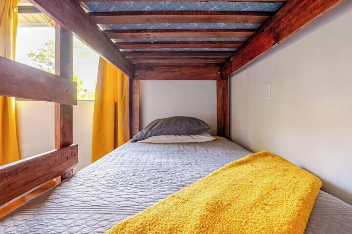 Una habitación pequeña con una cama, vigas de madera y una ventana con cortinas.