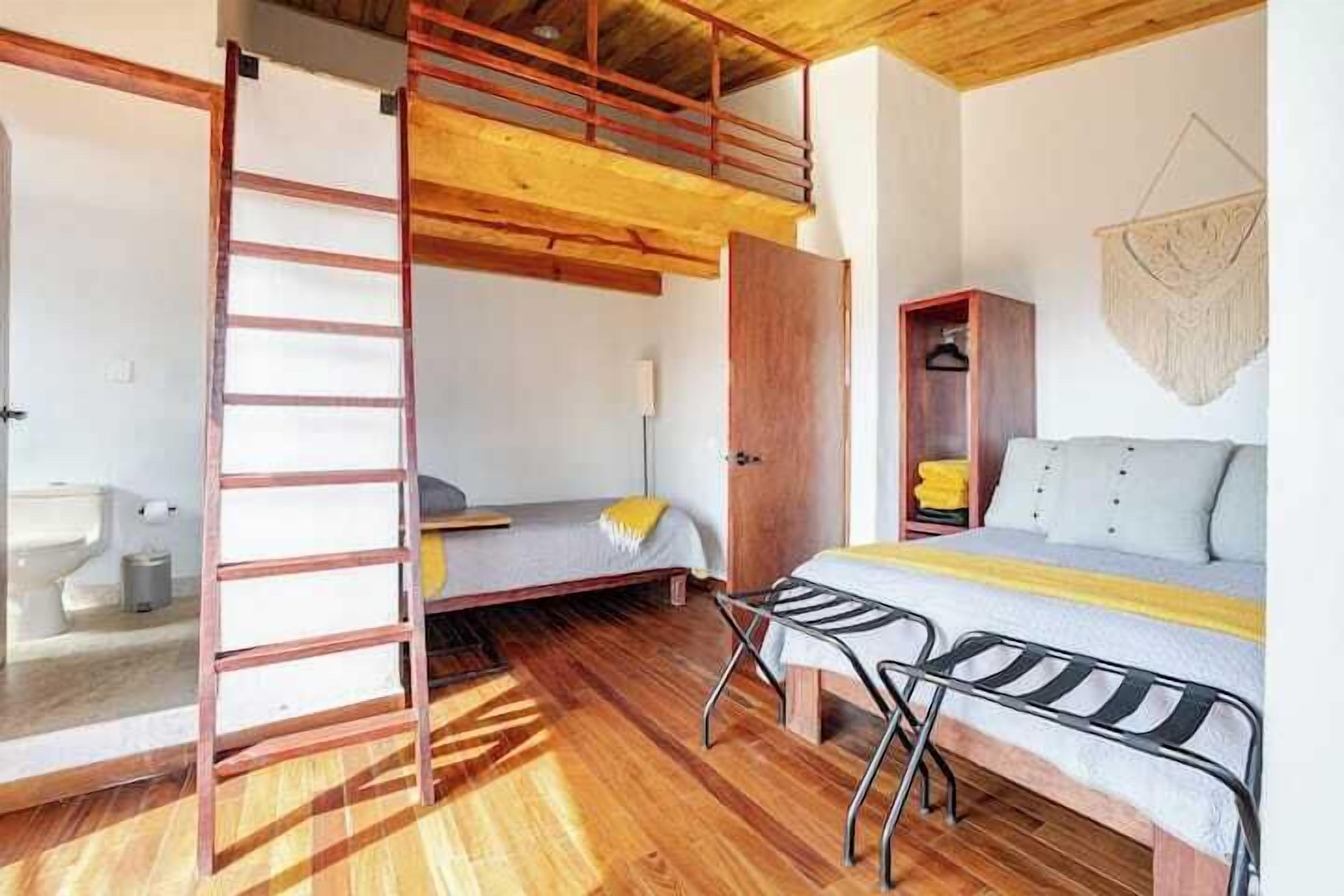 A compact room with a bunk bed, a small desk, and a wardrobe.