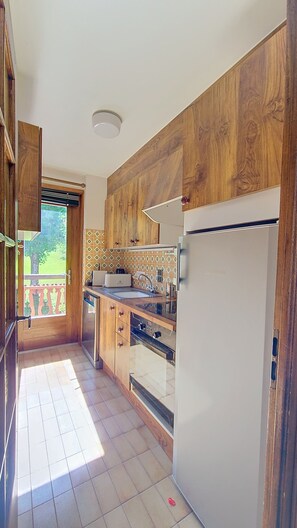 A kitchen with wooden cabinets, a built-in oven, and a refrigerator. - 1 Douny Apartment rental near the slopes Rochebrune area (Megève)