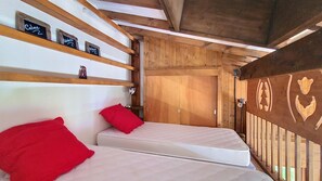 A room with two beds, wooden walls, and a door.