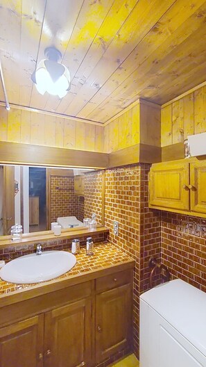 A bathroom with wooden cabinets, a sink, and a mirror.