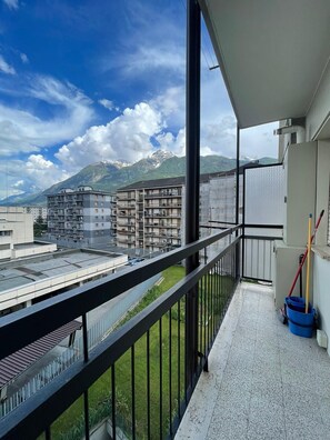 Uma varanda com vista para montanhas, edifícios e um céu claro.