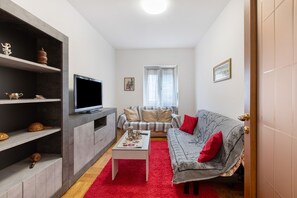Uma sala de estar com televisão, sofá e estantes.