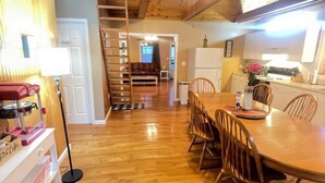 Un interior de madera con zona de comedor, cocina y escalera.